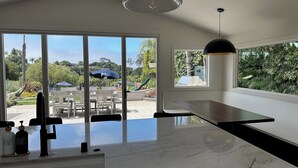 Eine moderne Küche mit Marmorarbeitsplatte, integriertem Spülbecken und Blick auf eine Außenpatio mit Stühlen und Sonnenschirmen.