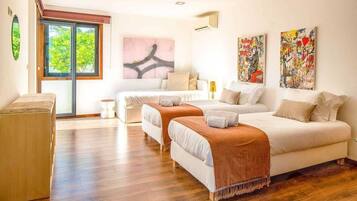A hotel room with two beds, a sofa, a small table, and artwork on the walls.