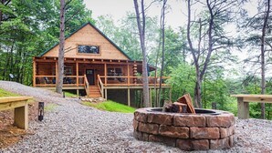 A log cabin with a deck, a fire pit, and a gravel path. - Louise's Hideaway by Inn & Spa at Cedar Falls (Logan)