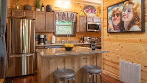 A modern kitchen with wooden paneling, stainless steel appliances, a granite countertop, and a large window. - Louise's Hideaway by Inn & Spa at Cedar Falls (Logan)