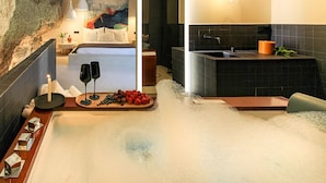A modern spa room with a hot tub, a wooden tray with fruits and glasses, and a painting on the wall. - Cave Suite COVA (Cave Hotel Lomas de Ruvira) (Jorquera)