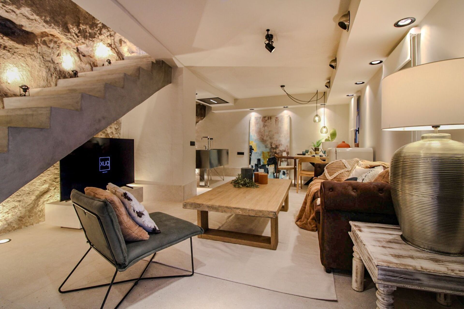 Een moderne woonkamer met een stenen muur, een houten eettafel, een bank en een televisie.