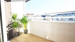 A balcony with two potted plants, a wooden floor, and a view of buildings in the distance. - The Paradise: Luxurious flat, parking, jacuzzi, terrace, new (Donostia)