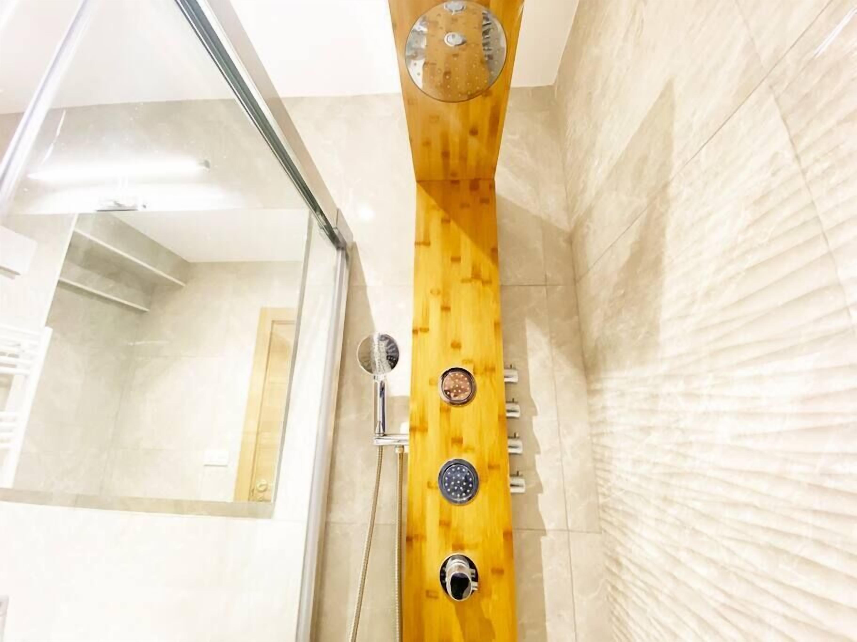 Un baño moderno con cabina de ducha de madera, puerta de cristal y pared de mármol.