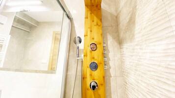 Un baño moderno con cabina de ducha de madera, puerta de cristal y pared de mármol.