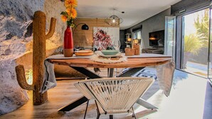 Un coin repas avec une table en bois rustique, une chaise en osier et une décoration à thème cactus.