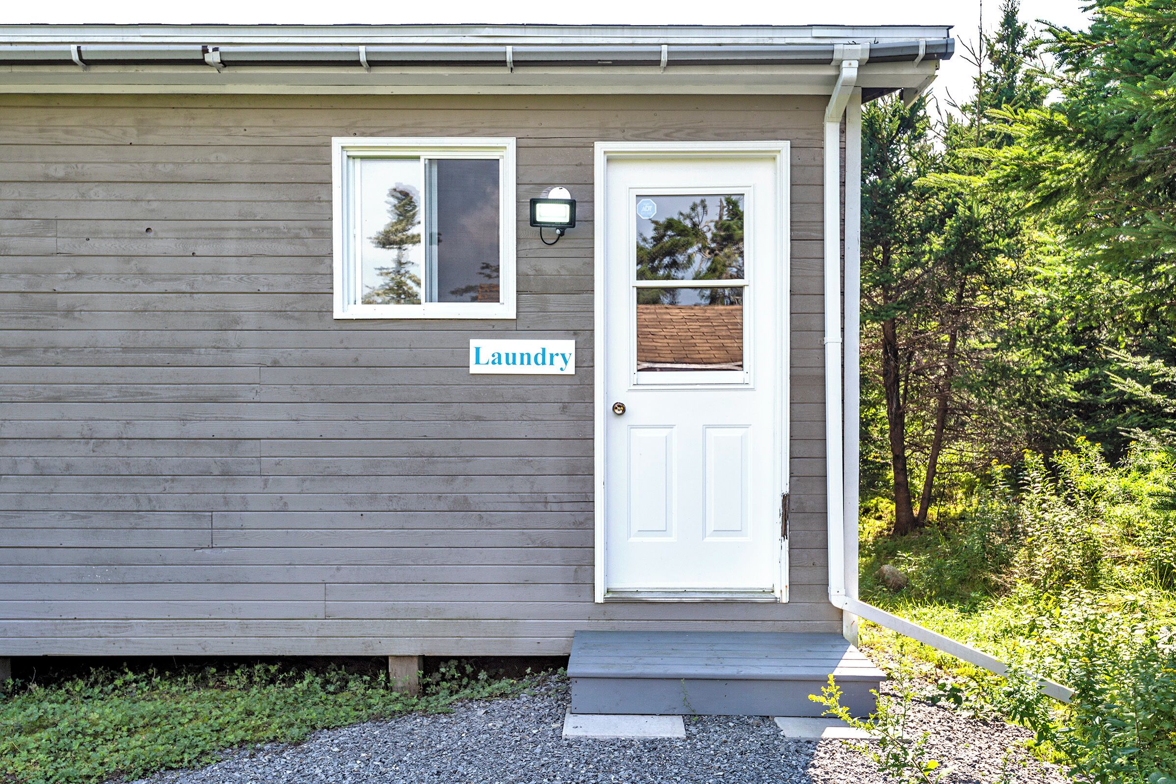 A small house with a white door and a window. There is a sign that says "Laundry" on the wall.