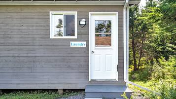 A small house with a white door and a window. There is a sign that says "Laundry" on the wall.