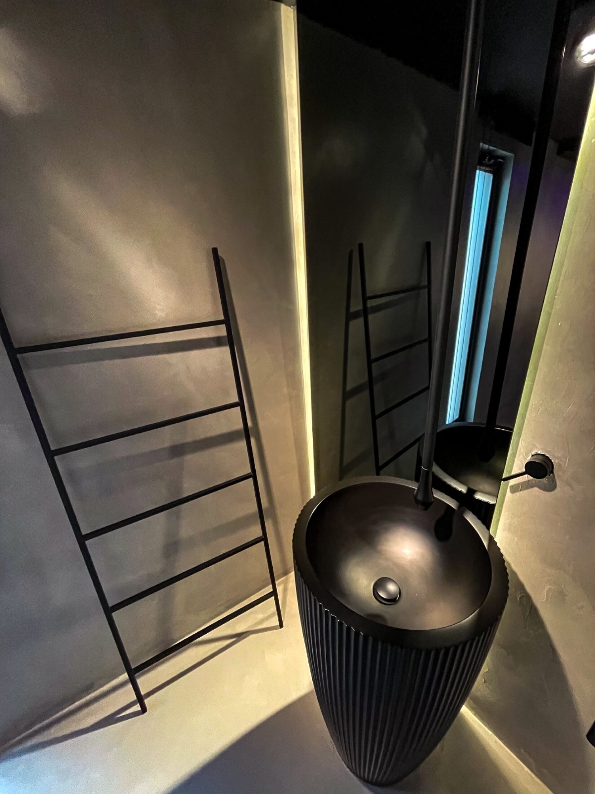 Une salle de bain moderne avec un lavabo noir, un porte-serviettes et un miroir.