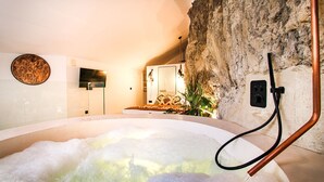 Un espace spa doté d’un jacuzzi, d’un mur en pierre et d’un aménagement intérieur moderne.