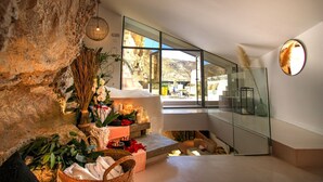 Un intérieur moderne avec un mur en pierre, une cloison en verre et une vue sur un paysage montagneux.