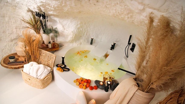 Un ambiente de spa con una bañera, velas y diversos productos de spa.
