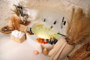 Entorn de spa amb banyera, espelmes i diversos productes de spa.