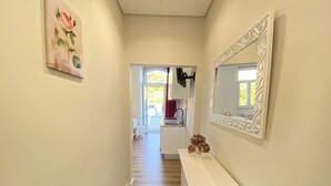 En hall med ett vitt konsolbord, en stor spegel och en tavla som föreställer en ros.