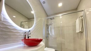 A modern bathroom with a red basin, a white toilet, and a glass-enclosed shower. - Canto Doce Portela - C (Setúbal)