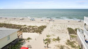 A beach with a building in the foreground, sandy beach, and ocean. - Awesome New, Dog-Friendly, Spacious Beach Home - Oak Island NC - Steps to ocean (Oak Island)