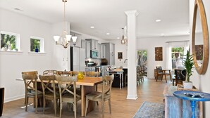 A spacious kitchen with wooden cabinets, a dining area with a wooden table and chairs, and a large mirror on the wall. - Awesome New, Dog-Friendly, Spacious Beach Home - Oak Island NC - Steps to ocean (Oak Island)