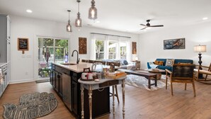 A spacious living area with a kitchen island, wooden flooring, and a blue sofa. - Awesome New, Dog-Friendly, Spacious Beach Home - Oak Island NC - Steps to ocean (Oak Island)