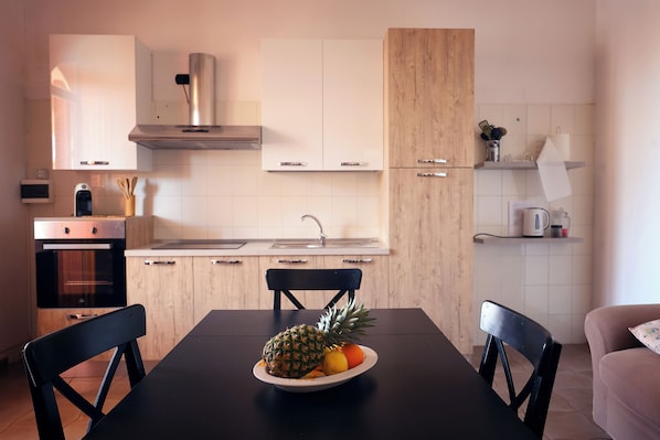 Cozinha moderna com armários de madeira, coifa de aço inoxidável e uma mesa de jantar com cadeiras.
