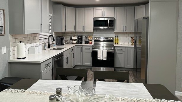 A modern kitchen with grey cabinets, a stainless steel oven, and a microwave. - King Bed, Clean & Cozy, 10 Min to WEC Ocala (Ocala)