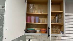 A kitchen with a white cabinet containing various glassware and dishes. - King Bed, Clean & Cozy, 10 Min to WEC Ocala (Ocala)