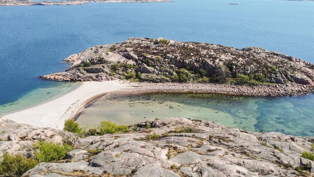 Una isla rocosa con una playa despejada y aguas turquesas.