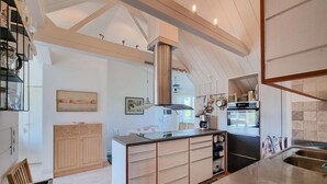 Una cocina moderna con una isla central, armarios de madera y una campana extractora de acero inoxidable.