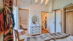 Un dormitorio con cama, cómoda con espejo, puerta de madera y baño con bañera.