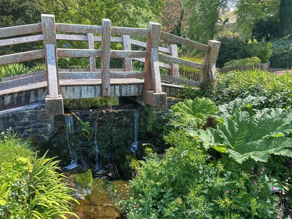 A wooden bridge over a small waterfall in a lush garden.