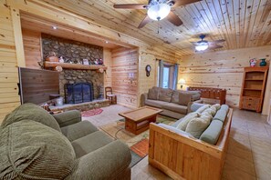 Ein gemütliches Blockhaus-Interieur mit Kamin, Holzmöbeln und Deckenventilator.