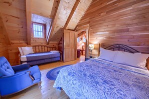 Une chambre confortable, aménagée dans un chalet en bois, avec un lit, une chaise, une petite table et une fenêtre.