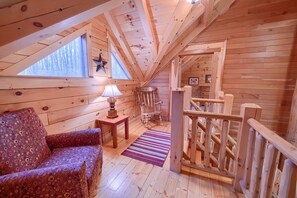 L’intérieur d’un chalet en bois chaleureux et accueillant, avec un canapé, une lampe, un fauteuil à bascule et une décoration en forme d’étoile sur le mur.