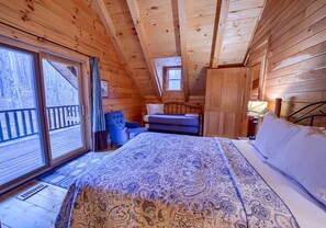 Une chambre dans une cabane en bois, avec un lit, une chaise et une fenêtre.