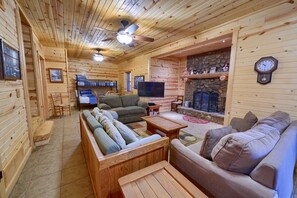 L’intérieur d’une cabane en rondins, avec une cheminée, des meubles en bois et un téléviseur.