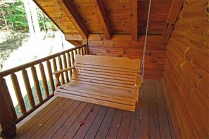 Eine Holzterrasse mit Schaukelstuhl, Holzgeländern und Blick ins Grüne.