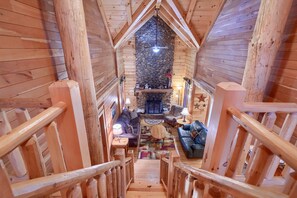 Un intérieur en bois agrémenté d’une cheminée en pierre, d’un escalier et d’un coin salon confortable.