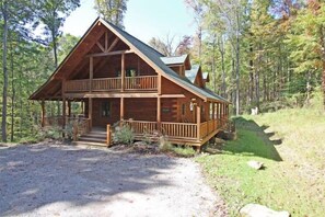 Une cabane en rondins à deux étages, dotée d’un balcon et entourée d’une forêt.