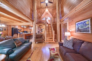 Ein Interieur einer Holzhütte mit Essbereich, zwei Sofas, einem Couchtisch und einer Treppe, die zu einer oberen Ebene führt.