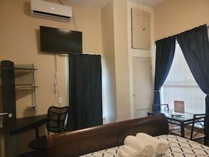 Relax in a clean and functional room with a comfortable bed, TV, and workspace.