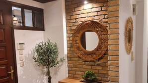 A hallway with a wooden desk, a potted plant, a mirror, and a stone floor. - Romantic traditional Villa with huge garden, swimming pool, basketball court etc (Avlonas)