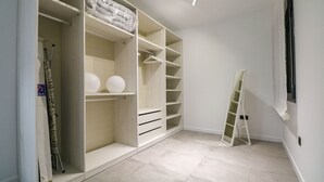 Un vestidor amplio con varias repisas y cajones, una escalera y un ventanal.