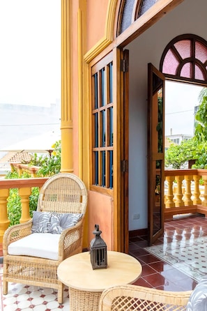 A balcony with wicker furniture, a lantern, and a view of greenery and buildings. - 2CM-B1 APARTAMENTO EN GETSEMANI CON BALC (Cartagena)