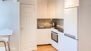 A compact kitchen with white cabinetry, a stainless steel sink, and a built-in oven. - Cozy apartment in Visby with kitchen (Visby)