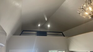 A room with a sloped ceiling, a chandelier, and a door leading outside.