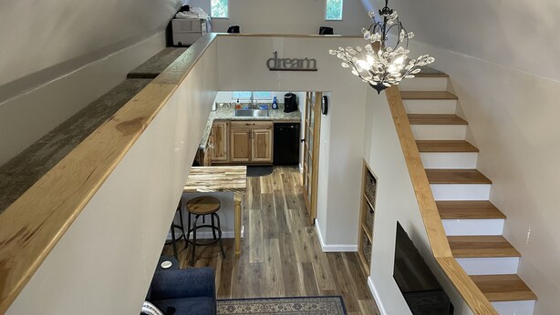 A modern loft-style interior with a kitchen, dining area, and a staircase.