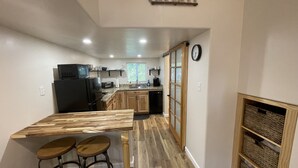 A compact kitchen with wooden countertops, a black refrigerator, and a dining area with stools.