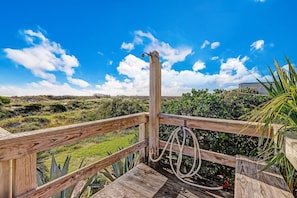 A wooden deck with a rope and a metal structure, overlooking a green landscape with bushes and a clear blue sky. - Beachfront 2BR • Pool • Direct Access (Fernandina Beach)