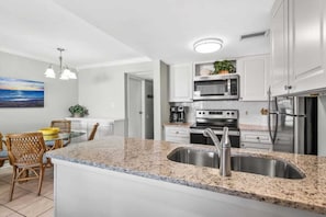 Eine moderne Küche mit Granit-Arbeitsplatten, Edelstahlgeräten und einem Essbereich mit Korbstühlen.