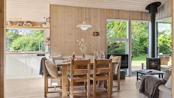 Un intérieur en bois comprenant un coin repas, une cheminée et de grandes fenêtres.