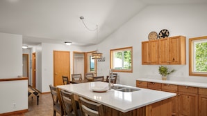 Una cocina moderna con armarios de madera, una isla grande y un comedor con sillas.